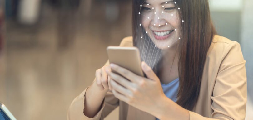 Woman using facial recognition on smartphone for secure digital identity verification in financial services