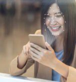 Woman using facial recognition on smartphone for secure digital identity verification in financial services