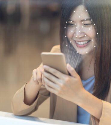 Woman using facial recognition on smartphone for secure digital identity verification in financial services